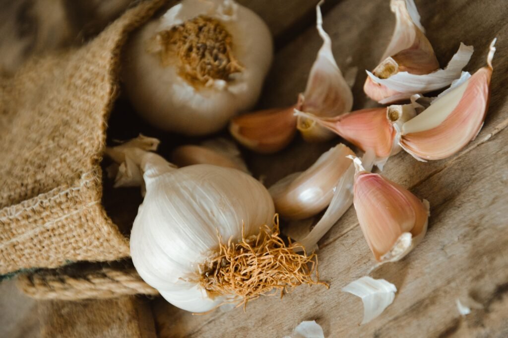 Fresh garlic bulbs and liquid castile soap on a wooden table for diy garlic mosquito spray recipe